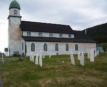 Exterior photo, nsouth facade, Holy Trinity Church, Codroy, Newfoundland, 2006, showing restoration work in progress and graveyard in the foreground.; HFNL 2006