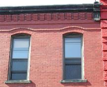 This photograph shows the roof-line cornice, corbel bands and an example of the style of window that is displayed throughout the façade, 2004.; City of Saint John