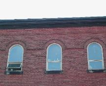 This photograph illustrates the roof-line cornice and roman arch windows, 2004; City of Saint John