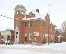 View of the front elevation of the Craik Town Hall featuring the brickwork and tower.; Saskatchewan Architectural Heritage Society, Frank Kovermaker, 2005.