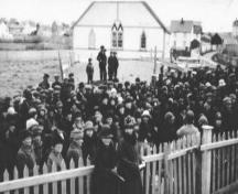 Historic image of crowd with Society of United Fishermen Lodge #9 in the background, circa 1942.  Photo taken from Christ Church property, Church Street, Bonavista, NL.; HFNL/ 2006