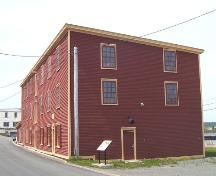 Exterior view looking west of the right and front facades of the Fishermen's Protective Union Factory/Advocate Building, Port Union, NL. Photo taken June 2006.; HFNL 2006