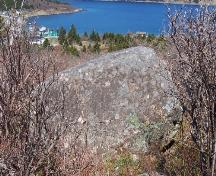 Southern side of Rock with 17th and 18th Century Graffiti showing Kingman's Cove, Fermeuse, NL in the background. Photo taken May 2006.; HFNL/Andrea O'Brien 2006