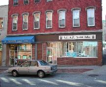 This photo shows the projecting storefront cornice and large fascia band. Also, entrances, windows, and transoms of the storefront, 2004; City of Saint John