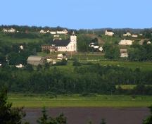 Photo prise du côté opposé de la rivière Petitcodiac montrant l'emplacement de l'église faisant face à la rivière; La Société historique de la Valleé de Memramcook