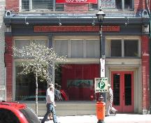 This photograph shows the storefront with large plate glass windows, cornice, and paired wooden doors, 2005; City of Saint John