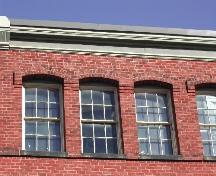 This photograph shows the roof-line cornice and six over six segmented arch windows, 2004; City of Saint John