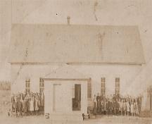 Photo of school children in 1912. The school was located on the site of the Higho de Cocagne Institutional Centre from 1876 to 1918 before being relocated in front of the stone church.; Valmond Léger Collection
