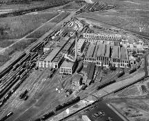 En 1936, les ateliers du chemin de fer Intercolonial appartenaient à CN, un employeur majeur à Moncton. Cette vue aérienne démontre la portée des opérations des ateliers.; Moncton Museum