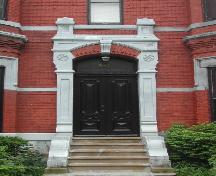 This image provides a view of the elaborate entablature with pronounced keystone supported by pilasters over the entrance, 2005.  ; City of Saint John