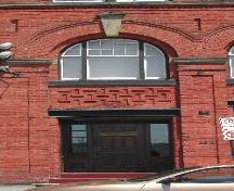 This photograph shows one of the entrances below a roman arch window, 2005; City of Saint John