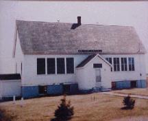Showing front facade with sign above porch and high pitched roof; Province of PEI