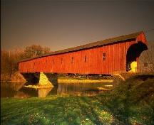 The West Montrose Covered Bridge, viewed from the south bank of the Grand River.; Ontario Tourism Marketing Partnership