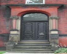 This image shows the Roman arch entrance, transom window and paired wooden doors, 2005. ; City of Saint John