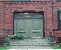 This image shows the projected, segmented arched entrance and transom window over the wooden doors, 2005.  ; City of Saint John