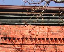 This image shows the wooden cornice with a decorative band of brickwork below, 2005.; City of Saint John