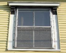 This image provides a view of a second storey window with an entablature supported by wood brackets, 2005.; City of Saint John