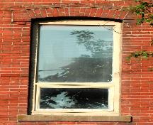 This image provides a view of a segmented arched window opening below a brick hood mould ending in corbel stops, 2005.; City of Saint John