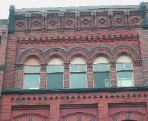 This photograph shows the bracketed cornice, the detailed brick design and Roman arch windows, 2005 ; City of Saint John