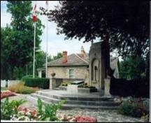 The John McCrae Monument and Memorial Gardens, with the John McCrae home in behind.; Beth McCracken, date unknown.