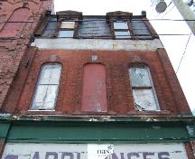 This photograph shows the dormers, the segmented arch windows and the storefront cornice, 2004; City of Saint John