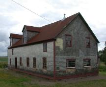 Corner view of the building illustrates the medium-pitched gable roof, slight roof overhangs of simple design, and gabled dormers typical of period small-scale industrial and farm buildings. ; PNB 2004