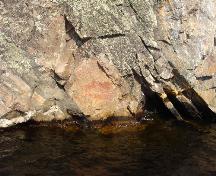 Vue des pictogrammes sur la surface de la falaise s’élevant abruptement à partir de la rive du lac au lieu historique national du Canada des Peintres-Rupestres-Mazinaw, 2008.; Agence Parcs Canada / Parks Canada Agency, Erica Lenton, 2008.