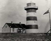 View of Cape Pine Lighthouse, showing the form and massing of the 15.3 metre high structure which consists of a tall, tapered tower with twelve-sided lantern.; Agence Parcs Canada / Parks Canada Agency.
