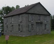 General view of Old Hay Bay Church, showing the two-storey, box-like, rectangular massing set under a medium-pitch gable roof, 2002.; Parks Canada Agency / Agence Parcs Canada, 2002.