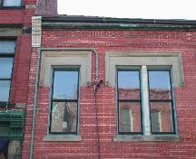This photograph shows the upper floor windows and the square hood moulding lintels, 2005 ; City of Saint John