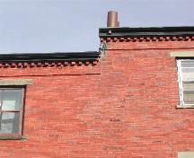 This photograph shows the roof-line cornice with dentils, and the staggered neighbouring building's roof-line, 2004; City of Saint John