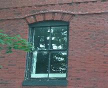 This photograph shows one of the segmented arch openings, with 2/2 vertical sliding wood window, 2005; City of Saint John