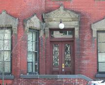 This photograph shows the entablatures and elaborate sandstone pediments on the windows and entrance, 2005; City of Saint John