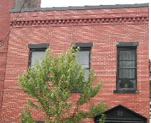 This photograph shows the roof-line with dentils, wood windows, sandstone sills and lintels, 2005; City of Saint John