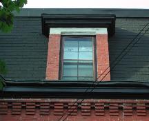 This photograph shows the roof-line cornice with corbel bands and a dormer window, 2005; City of Saint John