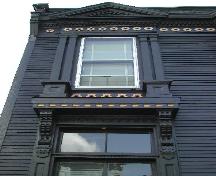 This photograph shows an upper window with Doric pilasters on each side, and illustrates the pediment above the frieze band, 2005; City of Saint John