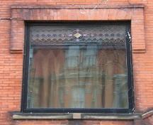 This image provides a view of the large first storey window with a stained glass transom and brick hoodmolding, 2005 ; City of Saint John