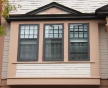 Cette image montre l'un des fenêtres en oriel d'un étage, surmontée d'un fronton et comprenant une fenêtre tripartite, 2005; City of Saint John