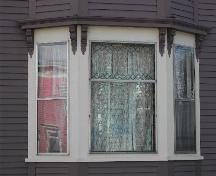 Cette photographie montre la fenêtre triple de la baie et les détails de style Arts and Crafts dans le carré supérieur de la fenêtre centrale, 2005; City of Saint John