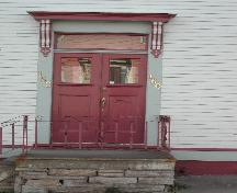 Cette photographie montre l'entrée de l'édifice qui présente un entablement à consoles au-dessus d'un imposte et les portes doubles en bois avec panneaux supérieurs en verre, 2005; City of Saint John