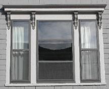 This image provides a view of the triple windows with an entablature supported by four, decorative scroll brackets, 2005; City of Saint John