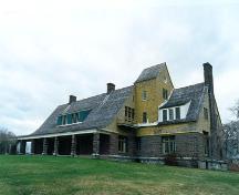 View of the façade of the Main House, showing Shingle styling and its roofline interrupted by a single dormer and deep front porch the length of the building’s central core, 1995.; Parks canada Agency/ Agence Parcs Canada, L. Maitland, 1995.