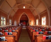 View of the interior of Tryon United Church, showing its interpretation of Gothic forms and detailing in wood, as seen in its faux-buttresses and its tripled Gothic arch stained glass windows, 1995.; Parks Canada Agency / Agence Parcs Canada, J. Butterill, 1995.