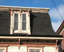 This photograph shows the mansard roof and the sharp flare that it possesses. The photo also shows a dormer window and artistic brackets, 2006; City of Saint John