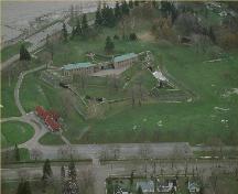 Vue aérienne du fort Érié, qui montre sa disposition sur un terrain plat gazonné donnant sur le lac Érié, à l’embouchure de la rivière Niagara, 1991.; Parks Canada Agency / Agence Parcs Canada, 1991.