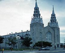 General view of Notre-Dame Roman Catholic Basilica, showing the twin-towered façade with large west window, 1989.; Parks Canada Agency / Agence Parcs Canada, W. Duford, 1989.