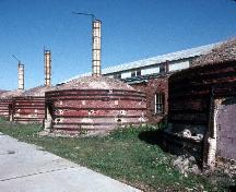 General view of Medalta Potteries, showing the beehive kilns with their brick exteriors, roof monitors, and roofing of wood shingles.; Parks Canada Agency / Agence Parcs Canada.