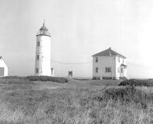 General view of Île-Verte Lighthouse, showing the spatial relationship of the lighthouse to the other buildings on the site, 1988.; Public Works / Travaux Publics, 1988.