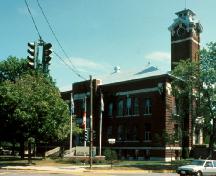 General view of Rivière-du-Loup Town Hall, showing the elements associated with town hall buildings, including its imposing central entry, square clock tower, and its brick facing material.; Parks Canada Agency / Agence Parcs Canada.