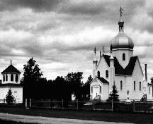 Vue générale de l'église ukrainienne St. Michael, qui montre les trois clochers à bulbe, surmontées de croix orthodoxes grecques.; Parks Canada Agency / Agence Parcs Canada.